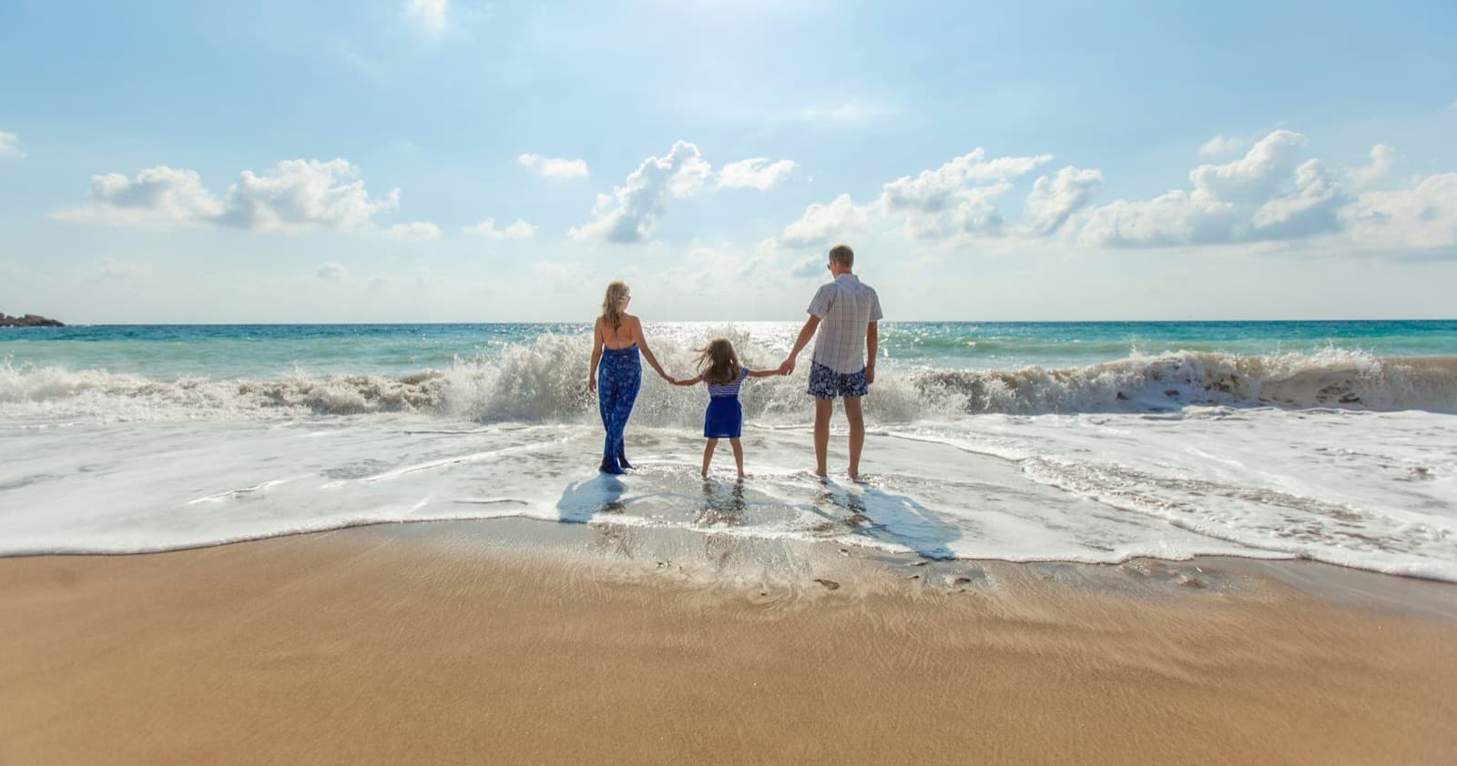 Familia caminando de la mano por la orilla del mar